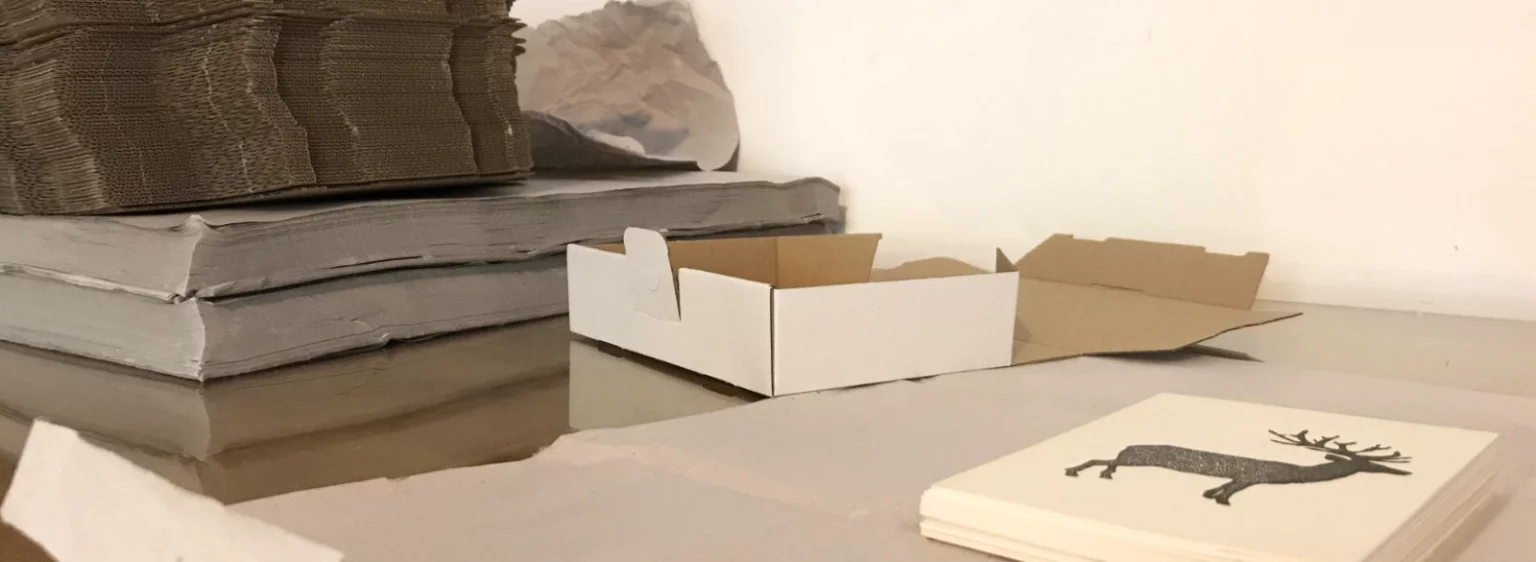 Versandvorbereitung: Kartons, Seidenpapier und Postkarte der Serie „Bio“ für sicheren Transport vom Fiete Rakete Shop.