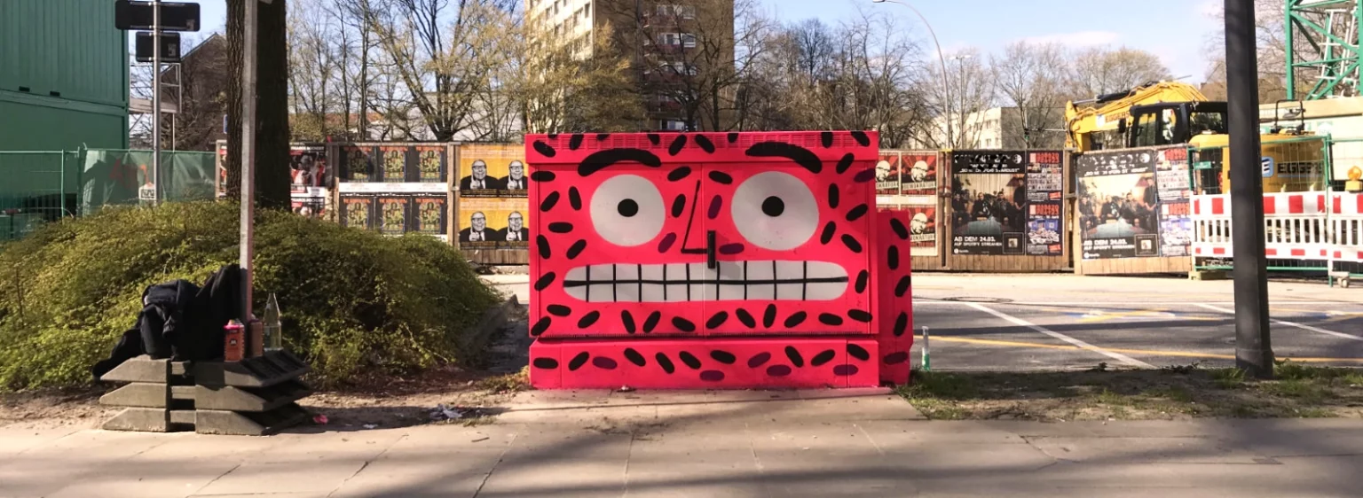 Frontalansicht eines farbenfrohen Stromkastens vor Hochhaus und Baustelle in Hamburg.