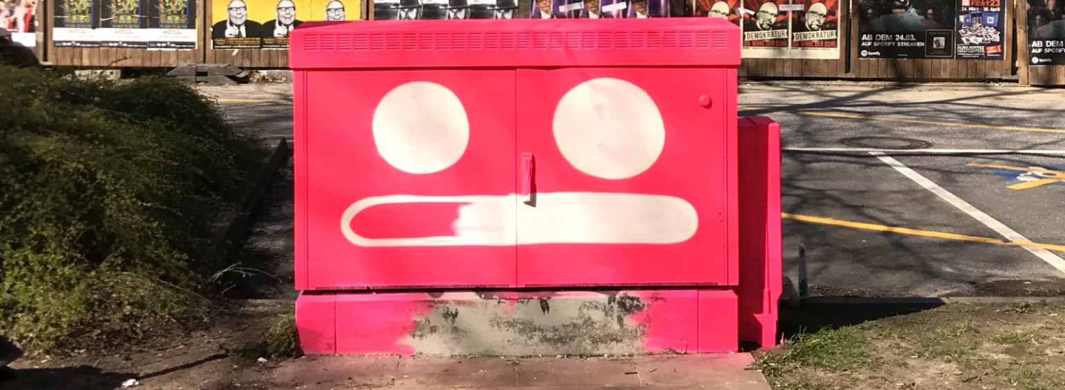 Stromkasten mit beiden Augen und beginnendem Mund, Vorderseite weiter ausgestaltet.