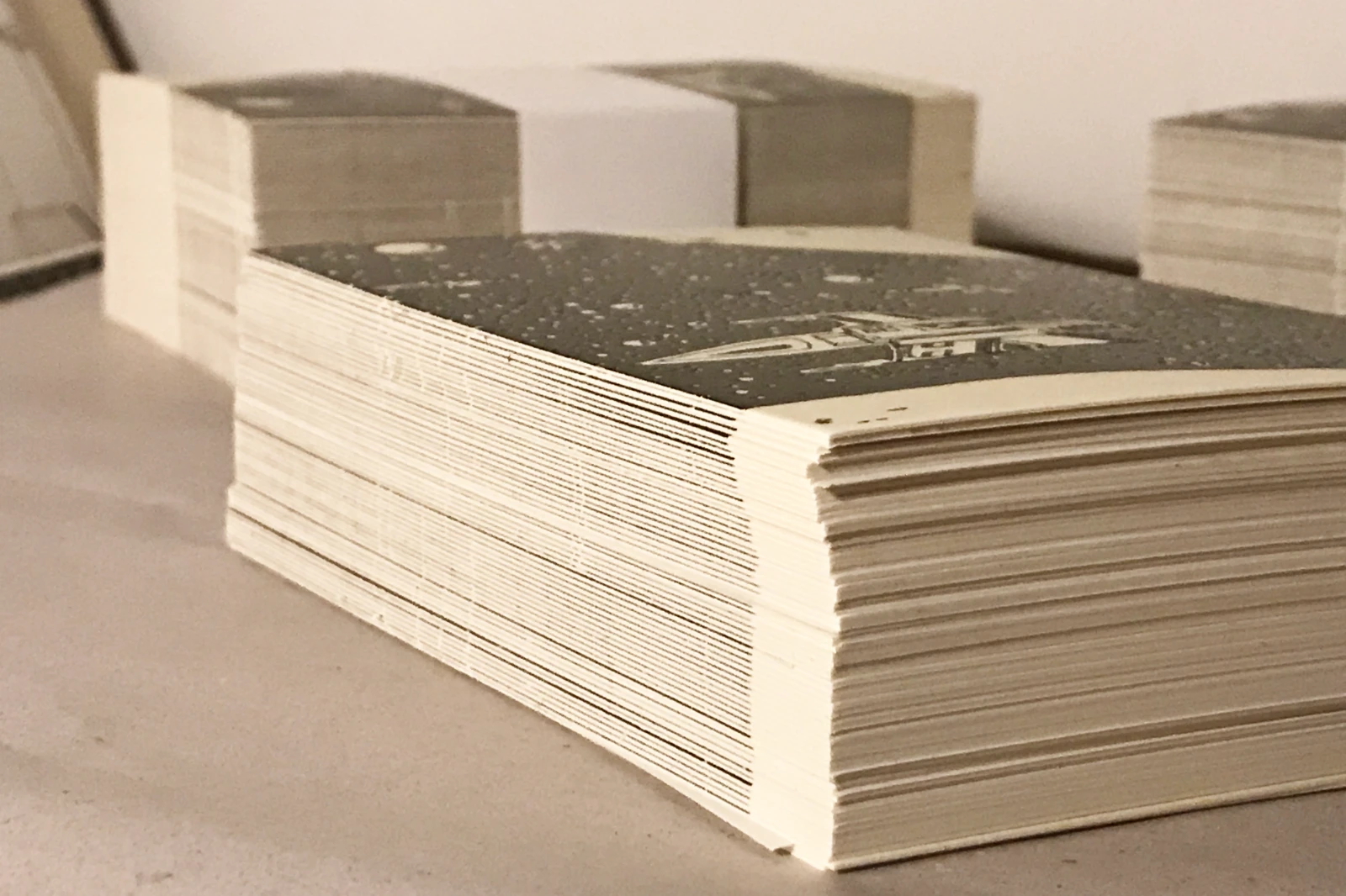 Stapel der Postkarten „Krom City – Sternenhimmel“ von Fiete Rakete, handgedruckter Siebdruck 105 × 148 mm, Schwarz-Weiß mit Glow-in-the-dark-Effekt, limitierte Edition