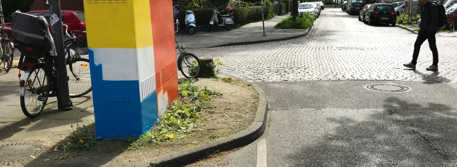 Passant:innen betrachten Stromkasten 2 während der Arbeit – neugierig und interessiert an der Straßenkunst von Fiete Rakete.