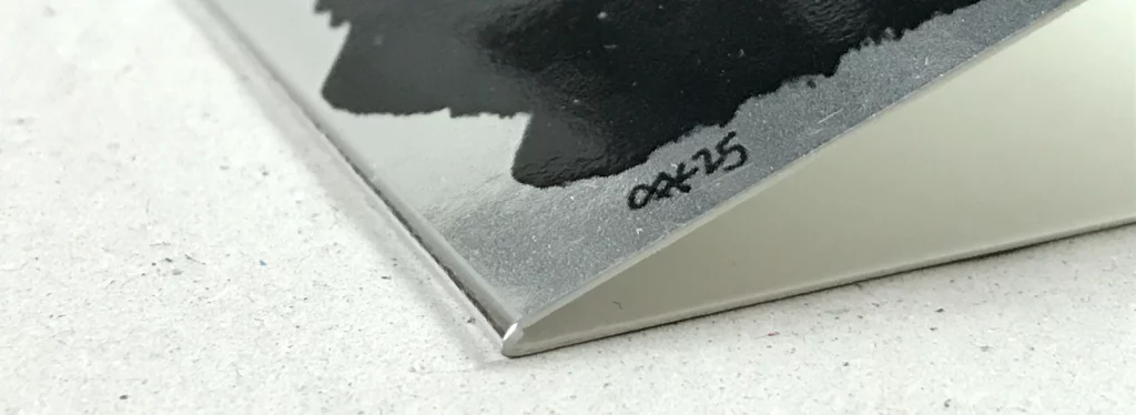 Nahaufnahme der Kante einer chromsilbernen Weihnachtskarte 2025, zeigt Materialstärke und saubere Verarbeitung.