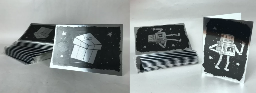 Stapel silberner Weihnachtskarten 2025, seitliche Ansicht, zeigt Materialstärke und Chromoberfläche.