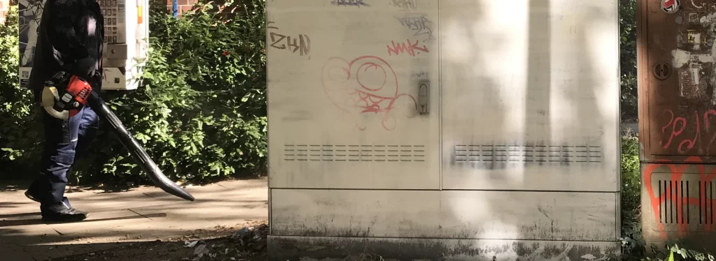 Laub wirbelt während der Bemalung eines Stromkastens durch die Luft