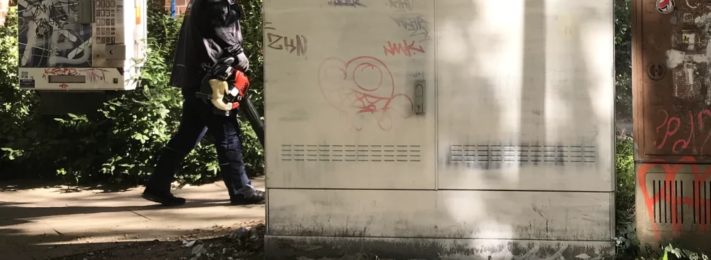 Herbstliches Laub wird durch Wind vor Stromkasten aufgewirbelt